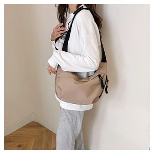 Detail of khaki nylon crescent bag featuring adjustable strap and woven zipper puller
