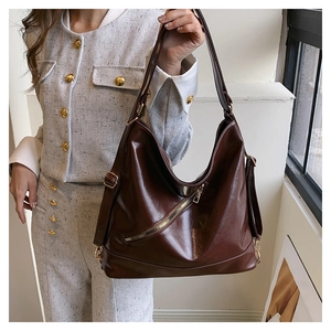Detail of dark brown faux leather tote with metal zipper and adjustable strap on model