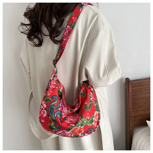 Close-up of red floral crossbody bag with traditional Chinese folk pattern on white coat
