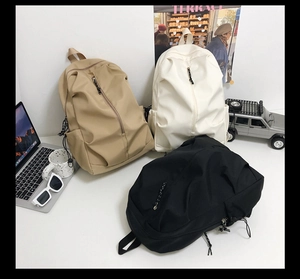 Three minimalist waterproof nylon backpacks in khaki, black, and white colors for students