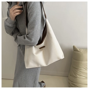 Detail of knit texture tote bag with brown leather handles and Fashion brand tag