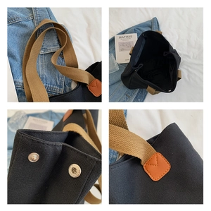 Close-up of black canvas tote with leather stitching and metal buckle details