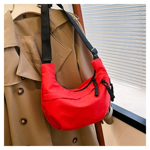 Detail of red nylon crescent bag with adjustable strap and woven rope zipper pulls