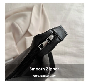 Detail shot of smooth silver metal zipper and fine stitching on black leather tote bag