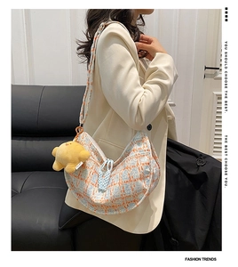 Detail of blue and orange checkered corduroy crescent bag with a cute bear charm