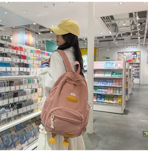 Detail of pink corduroy cartoon duck backpack with decorative yellow feet and front zipper