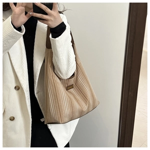 Detail view of striped tote bag with leather handles and textured woven fabric material