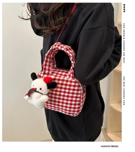 Detail of red gingham canvas bowling bag with a festive Snoopy-style plush pendant charm