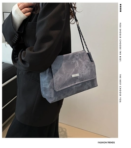 Detail of grey marble textured crossbody bag with chain strap and metal logo on the flap