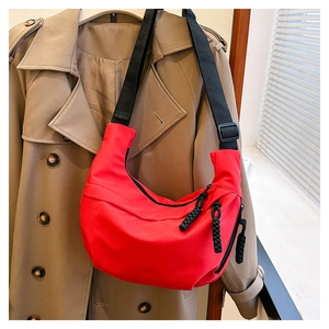 Close-up of red nylon dumpling bag with black zipper and woven rope pull detail