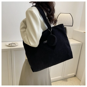 Close-up of black corduroy tote bag with round coin purse and fashion woven label