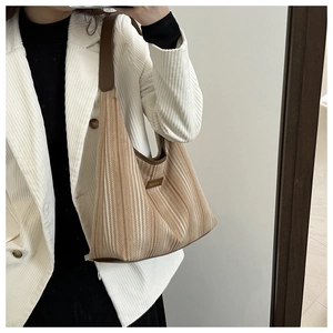 Detail of vintage striped corduroy tote bag with brown leather trim and metal logo