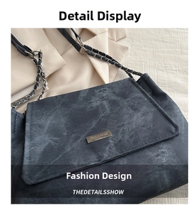 Close-up of deep blue denim texture shoulder bag with silver chain strap and metal logo