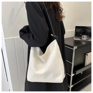 Detail of minimalist off-white large capacity bucket bag with black knotted shoulder strap