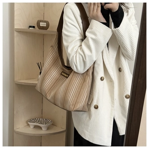 Brown canvas hobo bag with white stripes and a wide shoulder strap in a mirror selfie view