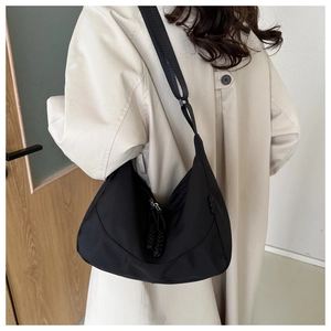 Detail of black nylon crescent shoulder bag with wide adjustable strap and dual zippers