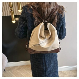 Detail of contrast color leather bucket bag showing side metallic zipper and brown base