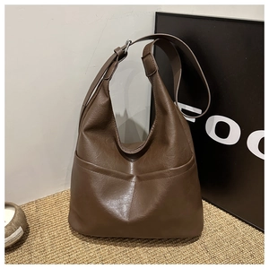 Detail of dark brown faux leather hobo bag featuring retro texture and front pockets