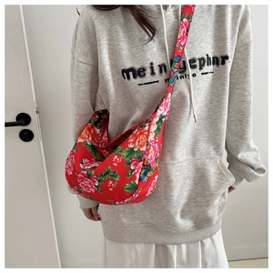 Detailed view of crossbody dumpling bag featuring vibrant red peony floral patterns