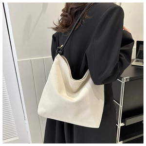 Minimalist beige tote bag with black rope shoulder strap on model in office setting