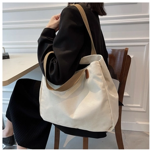 Detailed texture of high-capacity white canvas tote bag with brown contrast straps