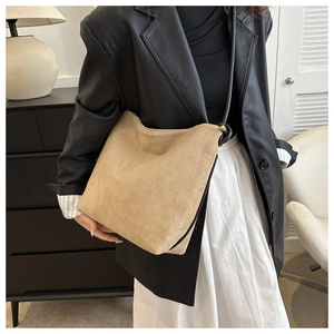 Macro detail of the matte khaki suede texture and slim black strap on this bucket bag