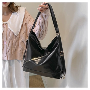 Detail of glossy black PU leather handbag with decorative diagonal metal zipper