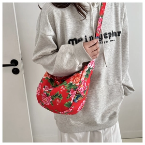Detail of red floral crescent crossbody bag featuring adjustable printed wide strap