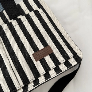 Fashionable black and white striped canvas tote bag with brown leather patch and straps