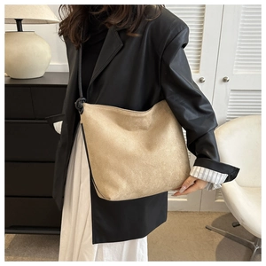 Detail of matte suede hobo bag in beige with black strap on a stylish model outfit