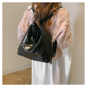 Detail of glossy black leather backpack with minimalist triangular shape and metal side zipper