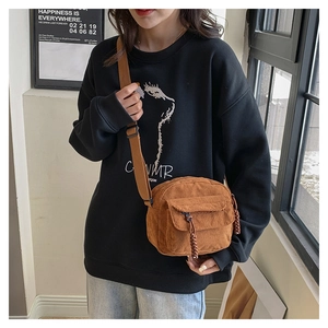 Lifestyle view of a caramel corduroy crossbody bag worn by a model with a soft window light