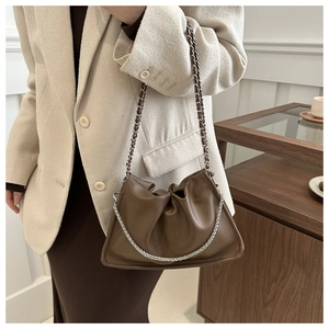 Détail du sac plissé en cuir marron foncé avec chaîne argentée et texture grainée