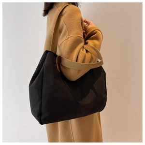 Detail of a black canvas tote bag showing the textured fabric and brown shoulder straps