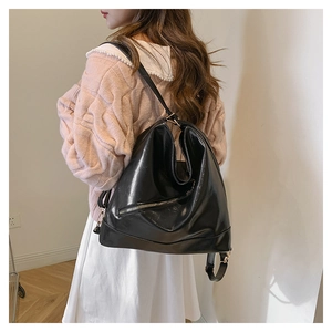 Detail of black glossy PU backpack with silver zipper and gold buckle on a model