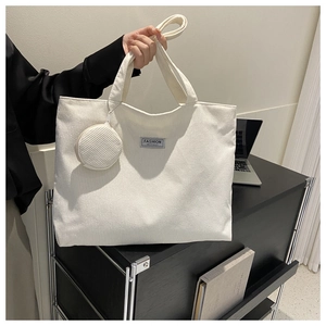 Detail of off-white corduroy tote bag with round pouch and fashion instinct label