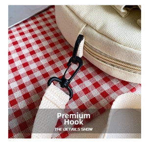 Detail of the black sturdy hook and woven strap on the beige canvas crossbody bag
