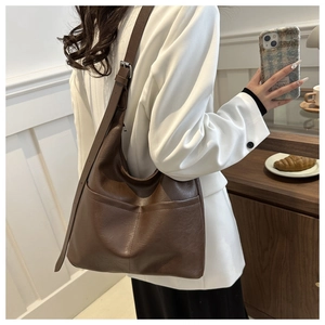 Side view of dark brown hobo tote bag with adjustable strap on a female model