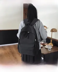 Sac à dos en nylon noir minimaliste porté par un mannequin dans un café chaleureux