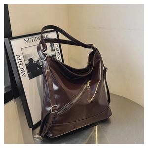 Detail of dark brown oily leather tote bag with stylish decorative zipper on metal stand