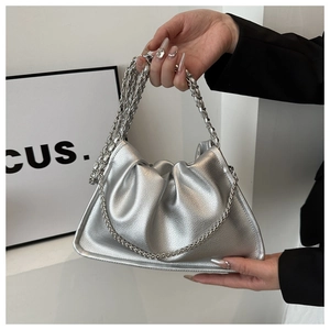 Macro shot of silver metallic ruched bag featuring a woven chain handle and grainy texture