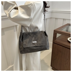 Detail view of the gray chain shoulder bag texture and metallic brand plaque on flap