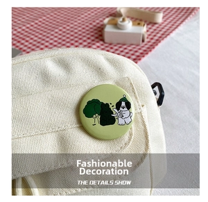 Close-up of a round green cartoon dog badge pinned on an off-white canvas bag