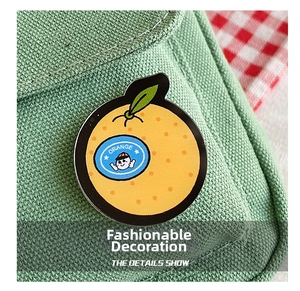 Nahaufnahme eines niedlichen Orangen-Ansteckers an einer grünen Stofftasche mit Details
