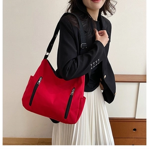 Detail of red canvas tote bag featuring dual black vertical zippers and adjustable strap