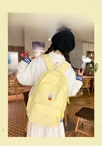 Detail of yellow canvas backpack showing the fashion label and smiley face patch