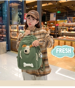 Detail of green corduroy backpack featuring plush dog decoration and adjustable straps
