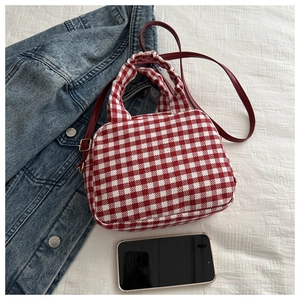 Detail view of red and white checkered canvas handbag with pleated handles and a leather strap