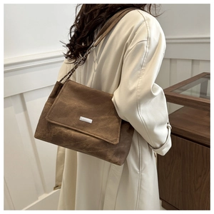 Detail of dark brown chain strap tote bag with textured vintage leather and silver logo