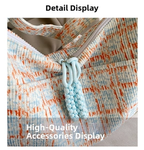 Close-up of corduroy checkered bag featuring a metal zipper and blue braided rope puller